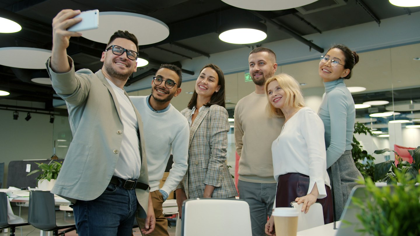 Team members take a selfie in a bright modern office.